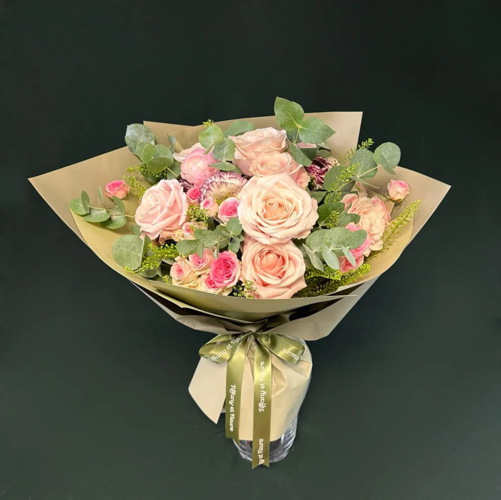 Elegant bouquet of soft pink roses wrapped in brown paper, tied with a satin ribbon, a romantic Valentine's gesture.