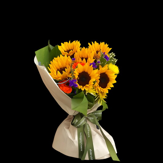 Bright sunflower bouquet with accents of purple statice, orange gerbera, and lush green foliage, elegantly wrapped and finished with Tiffany et Fleurs ribbon — a cheerful gift for any recovery or celebration.