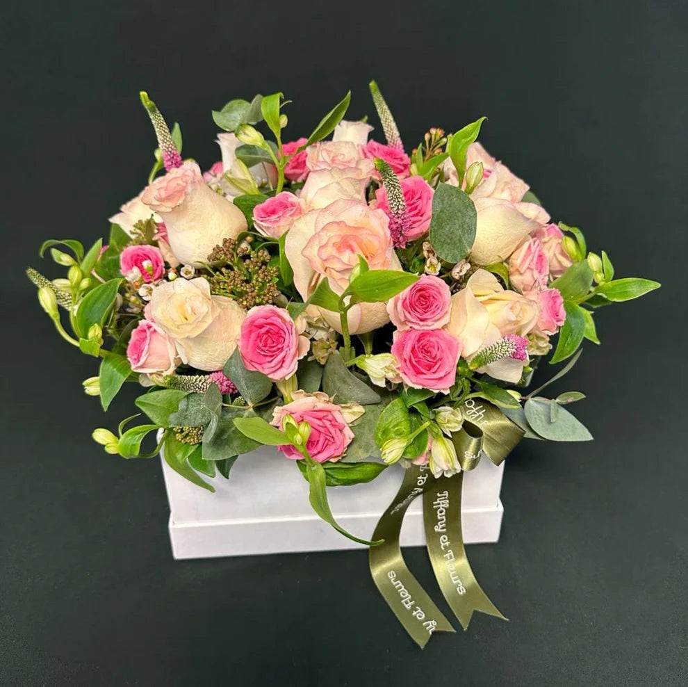 Valentine's Day mixed pink rose box with varied shades of pink roses and fresh green leaves, tied with a satin ribbon.